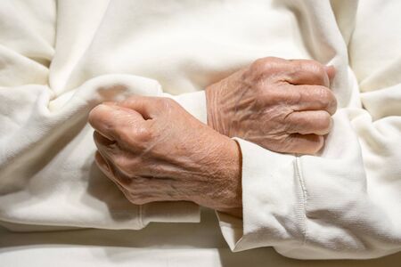 Hands of an elderly woman clenched in fists on her chest.の写真素材