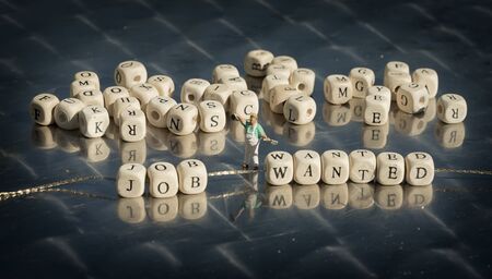 Miniature model of people and wooden cubes with job wanted inscription strung on a thread on reflective table.の写真素材