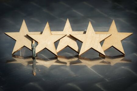 Miniature model of people businesswoman and five wooden stars, business presentation.