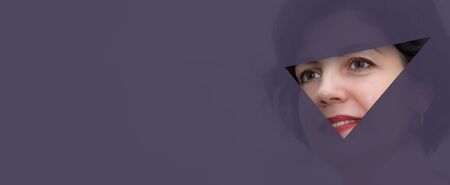 Pretty business woman, successful and confidence looks into the hole of translucent colored paper. Attractive middle aged woman with beautiful smile and copy space for your business card design.の写真素材