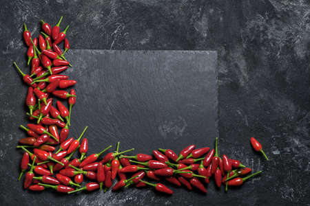 Red hot chilli peppers angle frame on a black table and black rock chopping desk, top view with copy space for your culinary text.の写真素材