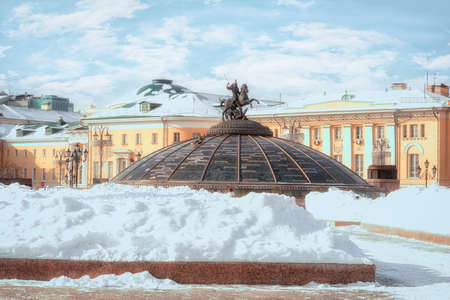 Snow pile at Manege Square. Glass cupola crowned by a statue of Saint George, holy patron of Moscow. (Inscription in Russian: names of famous cities in the world). Winter in Moscow, Russia.の写真素材