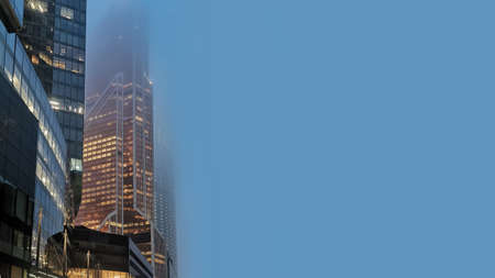 Skyscrapers in the fog with lighted windows with copy space for your text.の写真素材