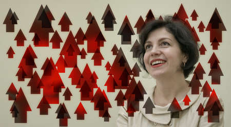 Successful confidence middle aged business woman looking up positive daydreaming laughing in business card with red up arrows.の写真素材