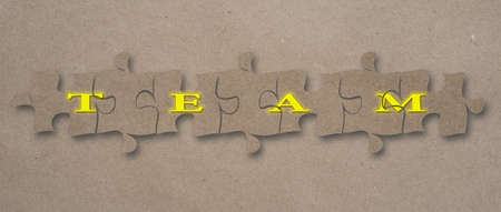 Team word assembled on puzzle pieces against a craft paper background.の写真素材