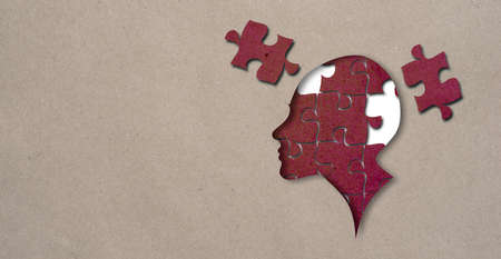 Cutout silhouette of a human head profile containing brain made from puzzle pieces craft paper jigsaw, incomplete or missing piece, revealing thinking conceptの写真素材