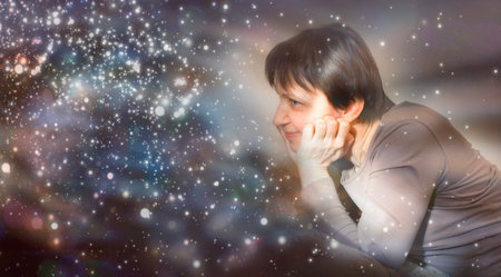 Woman looks at sparkles in anticipation of a miracle.の写真素材