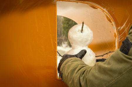 Hands put the snowman in a niche in the wall in the shape of the letter D. Preparing for the celebration of the new year concept.の写真素材
