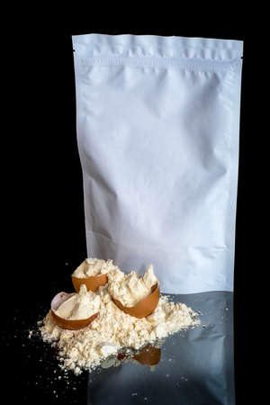 Egg protein powder heap and egg shells, white package mock up with copy space, isolated on black background with mirror reflection on the table. sports nutrition.の写真素材