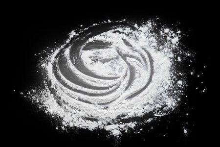 Pastry or recipe on a dark background sprinkled with wheat flour. Preparing for baking, top view on a black background or table. Preparation of dough or dough.の写真素材