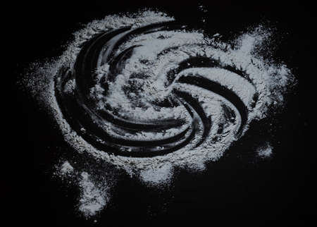 Black background sprinkled with flour speech bubble shape, smeared flour, table for cooking, rolling dough. Preparing for baking, top view isolated on a black background or table.の写真素材