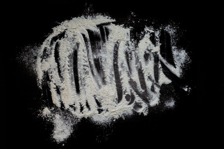 Pastry or recipe on a dark background sprinkled with wheat flour. Preparing for baking, top view on a black background or table. Preparation of dough or dough.の写真素材