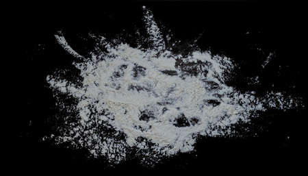 Black background sprinkled with flour, smeared flour, table for cooking, rolling dough. Preparing for baking, top view on a black background or table. Preparation of dough or dough.の写真素材