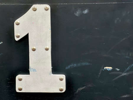 White wooden number one with nail heads on black background, copy space for your text.の写真素材