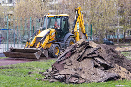 Moscow, Russia - May 04, 2022: Heap and JCB backhoe loader on a city street.のeditorial素材