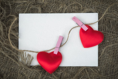 Greeting card with empty sheet of paper and two hearts attached with clothespins to a rope with copy spaceの写真素材