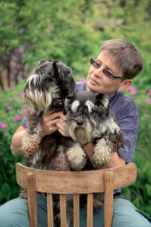 Woman sitting outdoor with two miniature schnauzer dogsの写真素材