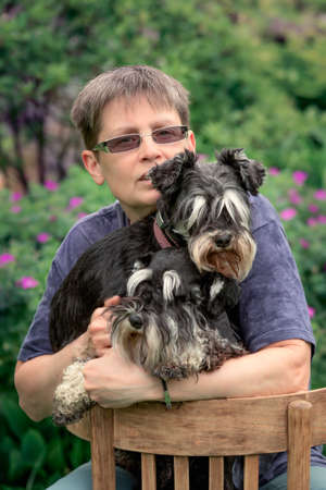 Woman sitting with two miniature schnauzer dogs outdoor.の写真素材
