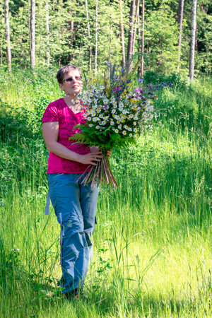 Woman holding huge bouquet of wildflowers, full length portrait.の写真素材