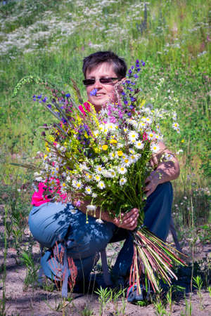 portrait of a happy smiling woman with a bouquet of wildflowersの写真素材
