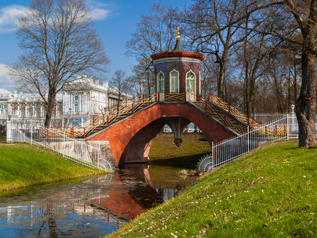 The Chinese-style bridge in the Alexander Park in Pushkin, St. Petersburg, against the backdrop of the palace in early spring in late April early May in clear sunny weatherの写真素材