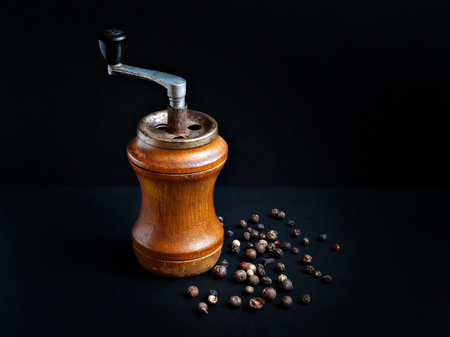 A wooden old pepper mill and dry bell pepper piled on a table on a black backgroundの写真素材