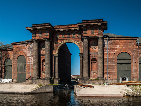 The architectural structure of the arch of red brick with columns, niches, portico rises on the island of New Holland near the river Moika in the city of St. Petersburg, Russiaの写真素材