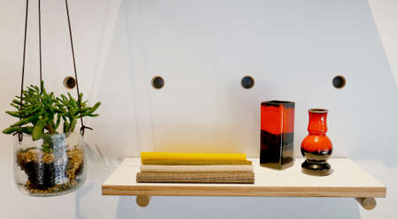 shelf with fabrics and plant hanging in a crystal vase