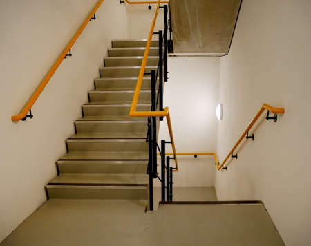 service staircase with marked steps and yellow and black handrailの写真素材