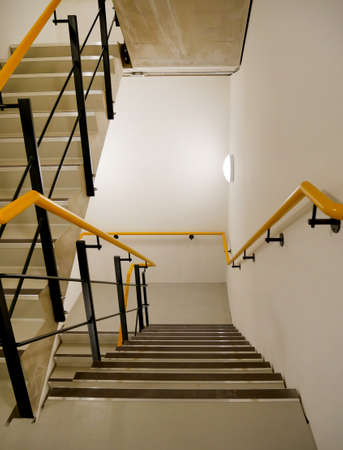 service staircase with marked steps and yellow and black handrailの写真素材