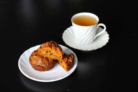 Carrot cakes with walnuts and spices, next to a white porcelain Cup of green tea.