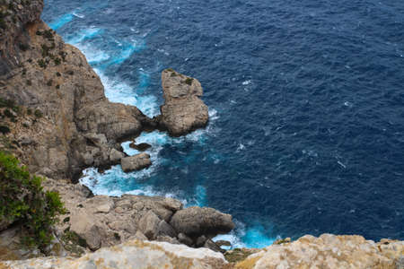 On a precipice. View from the cliff on the waves breaking on the shore. Cape Formentor. Majorca. Spain.の写真素材