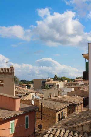 tiled roofs of houses in Alcudia against a blue sky with clouds. Alcudia. Majorca. Spain.