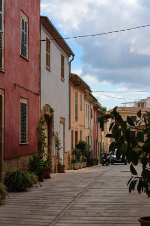 A paved street with colorful houses and flowers in pots along the walls. Majorca.