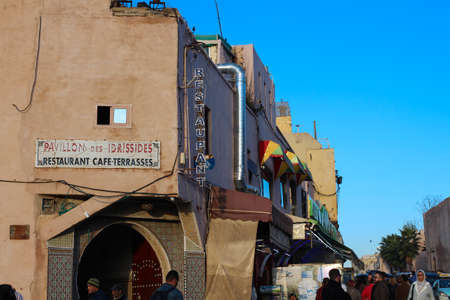 MEKNES / MOROCCO-12.06.2019.Meknes street with old houses, a restaurant, mosaics and lots of people.