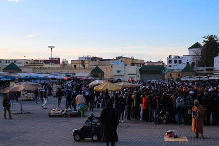 MEKNES.MOROCCO.Market on El Hedim square. A crowd of people looks at street performers, a man in...