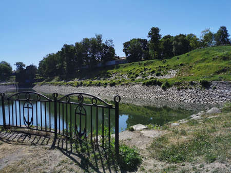 Cast-iron fence with anchors on the shore of the Dock pool in the Summer Garden of the city of Kronstadt against the background of a cloudless skyの写真素材