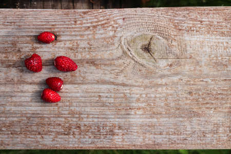 Five ripe, fresh, wild strawberries on a wooden Board.の写真素材