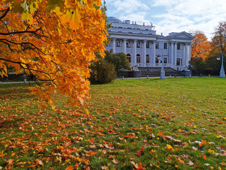Maple with orange, bright, autumn leaves against the background of the Elaginoostrovsky Palace with columns, stairs and lions in a park on the Elagin Island of St. Petersburg.のeditorial素材