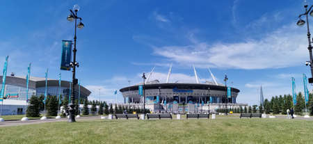 Lawn and benches in front of the Gazprom Arena stadium in St. Petersburg on the morning of the match day of the EURO 2020 European Football Championship against a blue sky with clouds.のeditorial素材
