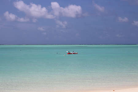 Morning in the Maldives, a man and a woman are sailing on a kayak along the coast of the Indian...