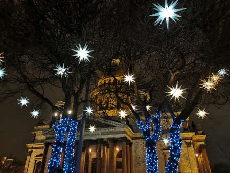 St. Isaac's Cathedral in St. Petersburg through the trees decorated with stars and garlands for Christmas and New Year on an early winter morning.のeditorial素材