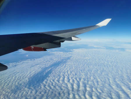 View from the porthole on the wing of an airplane flying to Cyprus with a red aircraft engine, in...