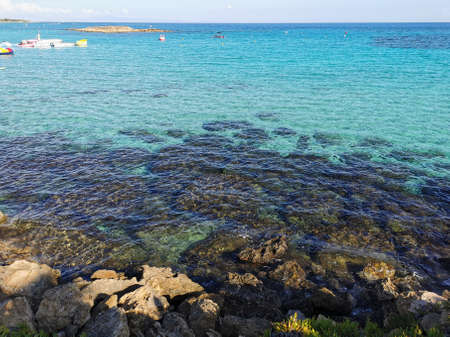 View of the clear water of the Mediterranean Sea, the pier on the Fig Tree Bay beach with a boat and catamarans and the island.の写真素材