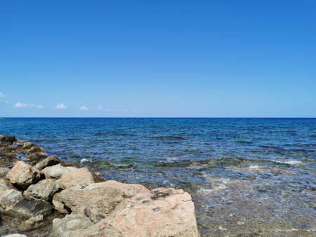 Protaras. Famagusta area. Cyprus. The coast of the Mediterranean Sea, waves, clear water, a stone ridge against a blue sky with clouds.の写真素材