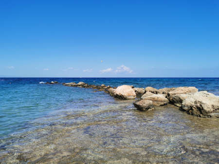 Protaras. Famagusta area. Cyprus. The coast of the Mediterranean Sea, waves, clear water, a stone ridge against a blue sky with clouds.の写真素材