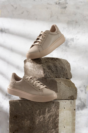 Comfortable sneakers on stone. Concept active lifestyle, casual, shoes, business woman, handmade, vertical.の写真素材