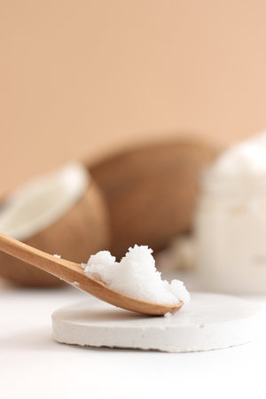 scrub in wood spoon with jar coconut on white and brown background. Home spa treatment concept, organic cosmetic.の写真素材