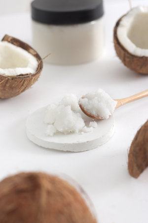scrub in wood spoon with jar coconut on white background. Home spa treatment concept, organic cosmetic. Vertical photoの写真素材