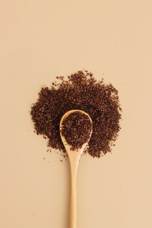 Brown texture scrub with cocoa coconut coffee in wooden spoon on brown background. spa and home care concept, beauty procedures, vertical photo.の写真素材